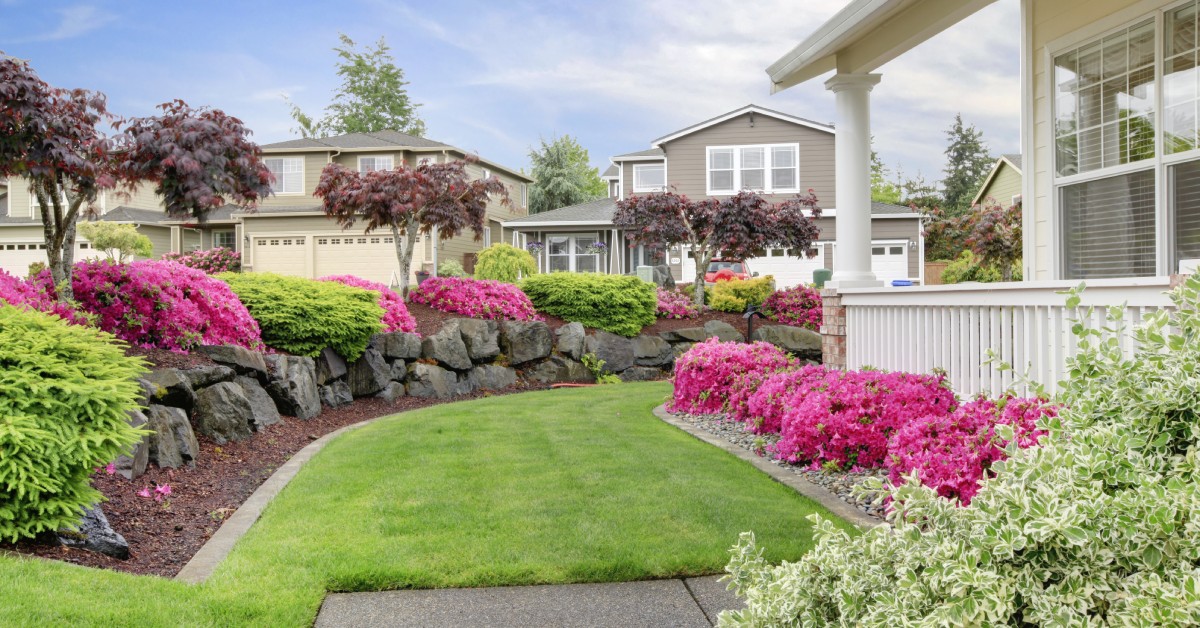 A residential home with a freshly-cut lawn and colorful plants growing in well-manicured flower beds.